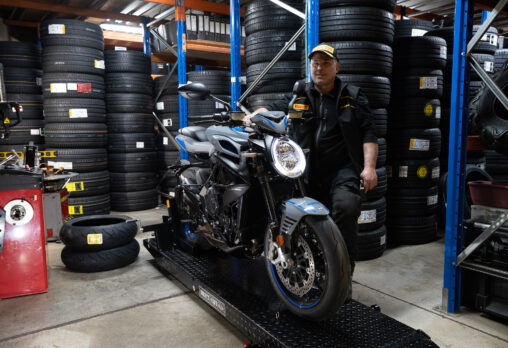 An Image of a motorcycle technician standing next to a motorcycle