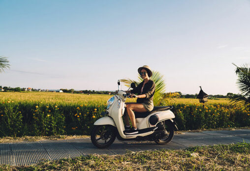 a woman riding a moped on the street