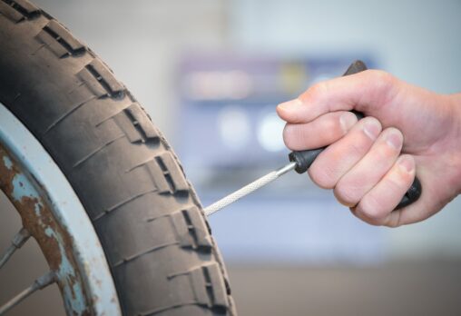 A motorcycle tyre being plugged with a tyre repair kit