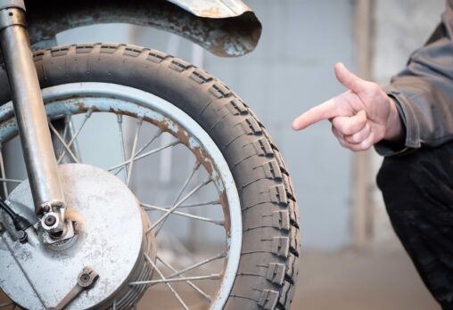 A hand pointing at a motorcycle tyre