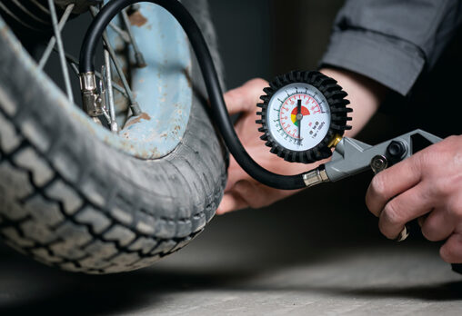 a close up photo of a person monitoring the air pressure of a motorcycle tyre